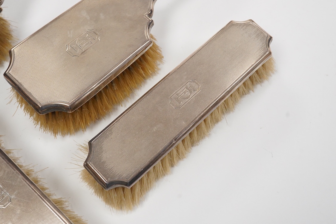 A 1930' matched engine turned silver mounted four piece dressing table brush set, William Comyns & Sons Ltd, London, 1933,36,38 & 39.
